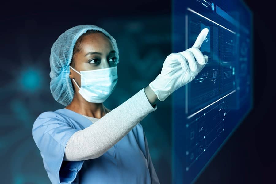 A woman in a surgical mask and gloves points at a screen displaying surgical instruments.