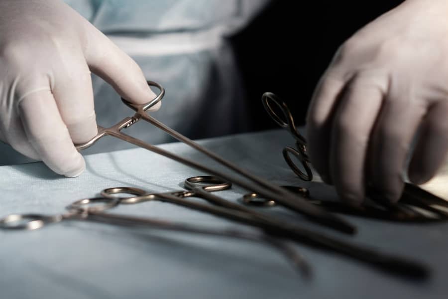 Surgeon's hands holding scissors for surgical instrument maintenance.